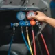 Auto technician using pressure gauge to diagnose car AC refrigerant levels and system performance