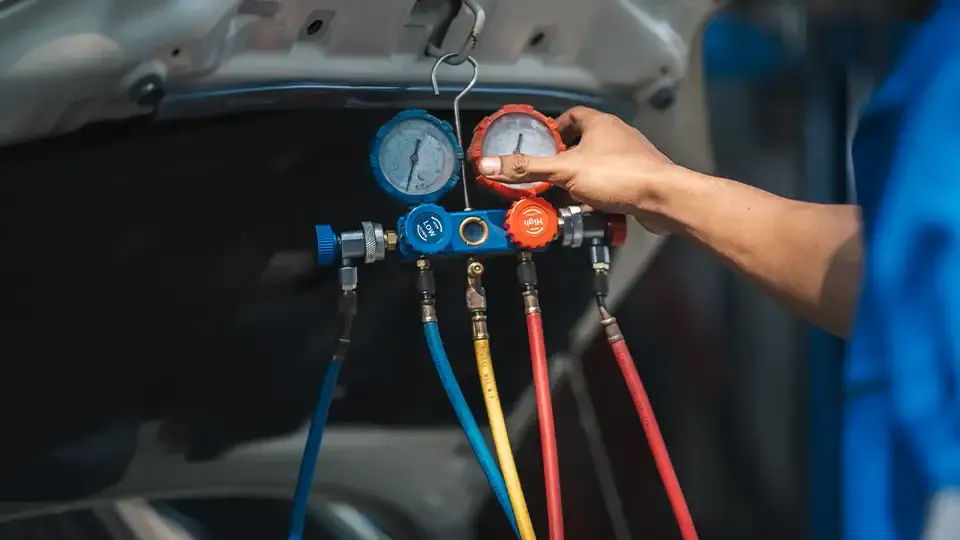Auto technician using pressure gauge to diagnose car AC refrigerant levels and system performance
