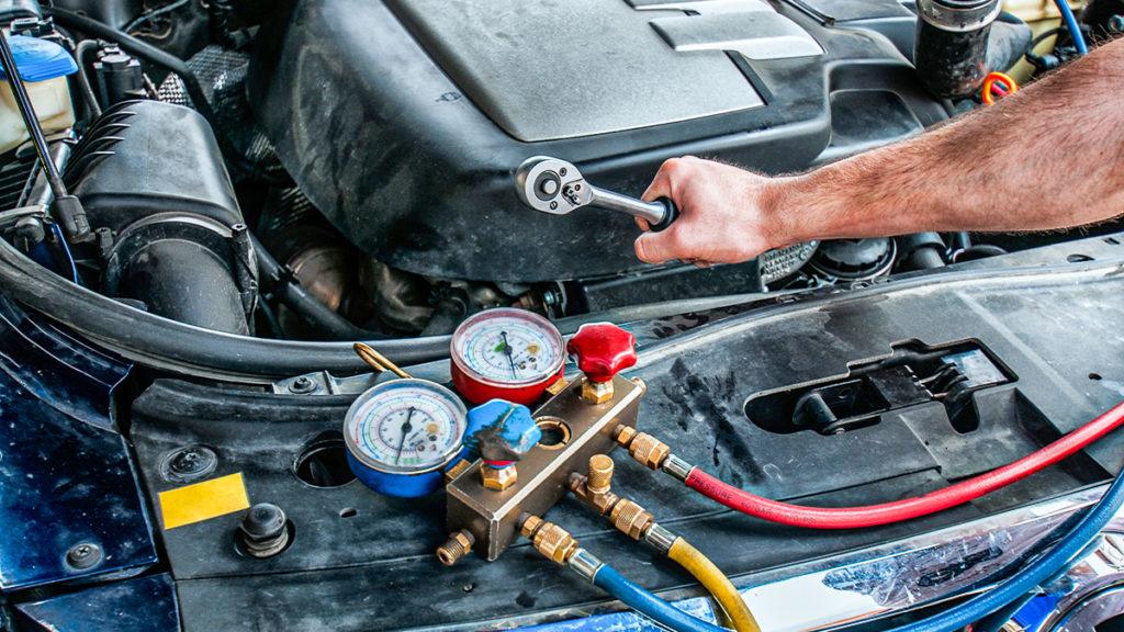 ASE certified mechanic diagnosing car air conditioning system in auto repair shop