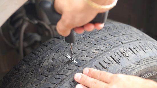 Tire technician performing a professional patch repair on a flat tire