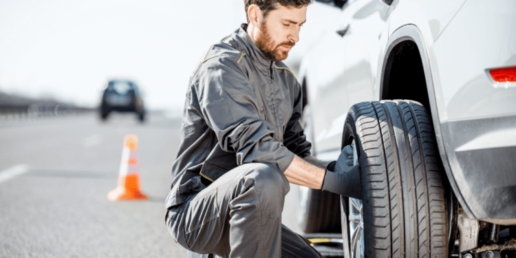 Mobile tire service technician changing a flat tire on the roadside
