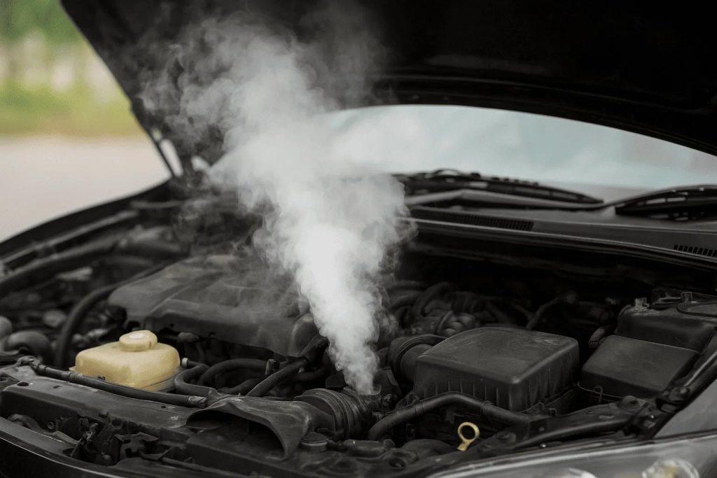 A car with its hood open has white smoke rising from the engine, suggesting overheating or a mechanical issue—prompt attention to cooling system service and repair may be needed.
