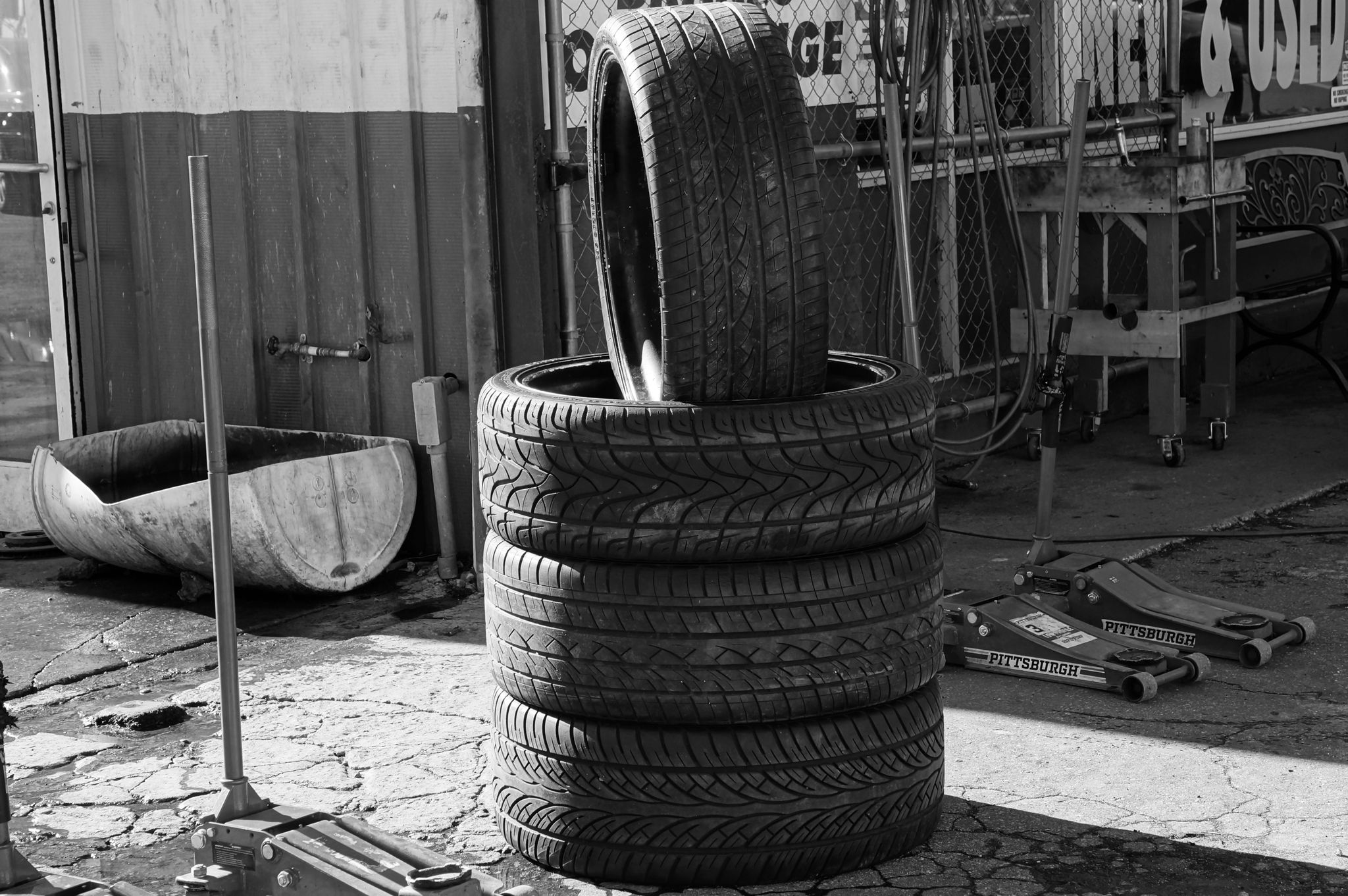 Black and white photo of stacked tires in a garage environment highlighting industrial themes.