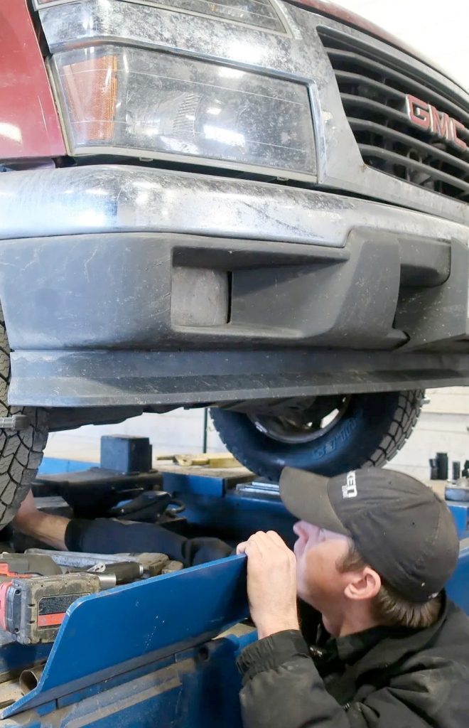 mechanic looking under truck on a lift